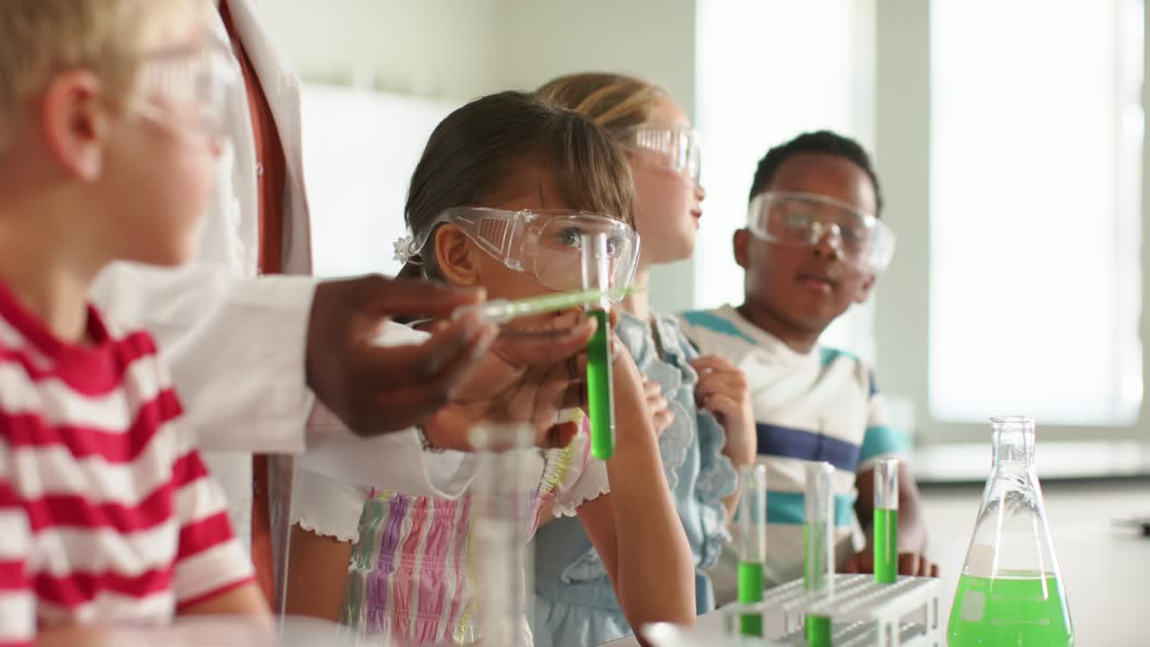 Children watching African American woman teacher showing green test tube at lab bench, observing