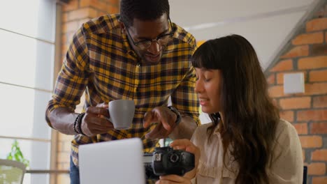 Graphic-designers-reviewing-photographs-on-digital-camera-at-desk-4k