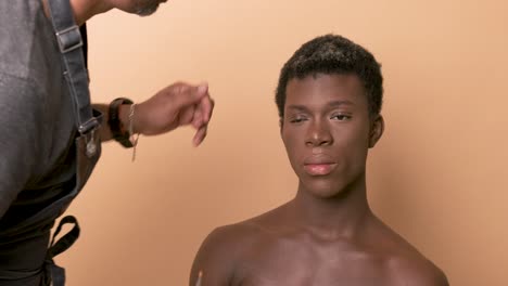 visagiste applying lipstick while doing makeup on transgender preparing for photo shoot