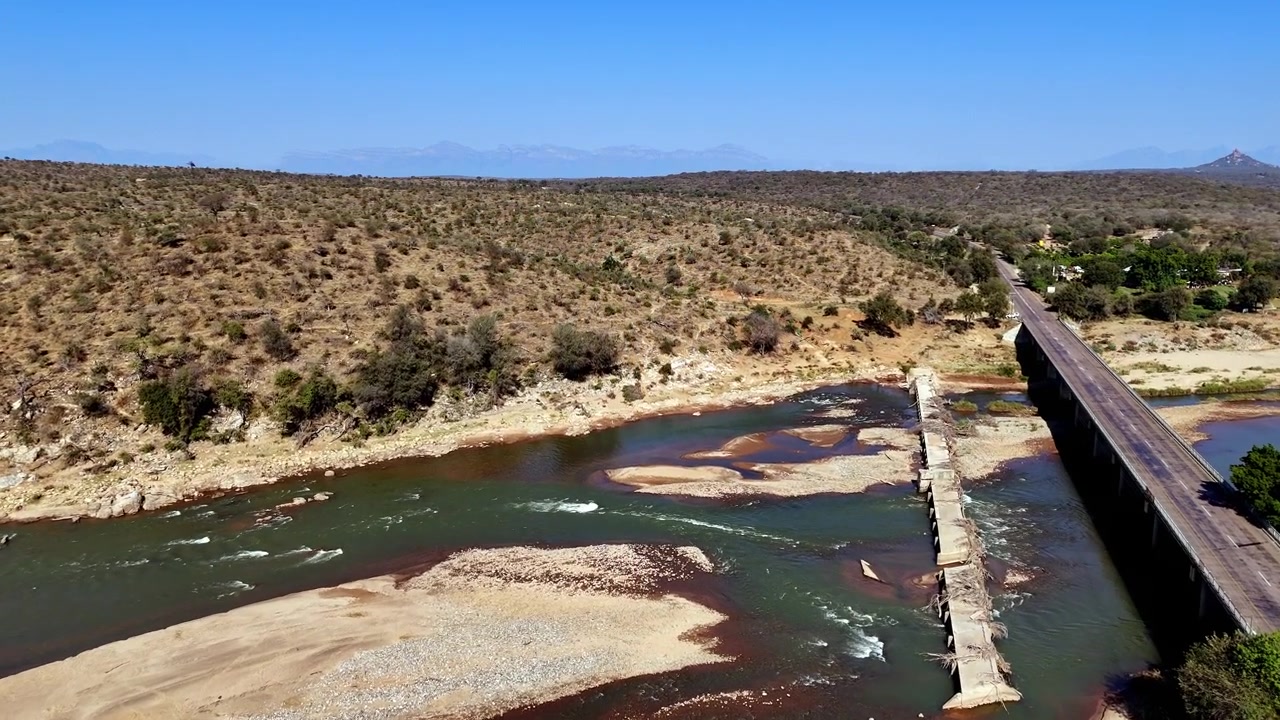 Ponte stradale asfaltato accanto a un vecchio ponticello inutilizzato che attraversa un fiume africano. Ripresa con drone.