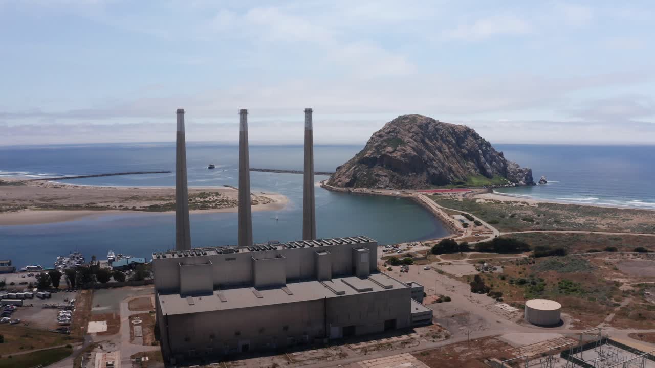 tomada aérea de la abandonada central eléctrica de morro bay con sus famosas tres chimeneas frente a morro rock en morro bay, california