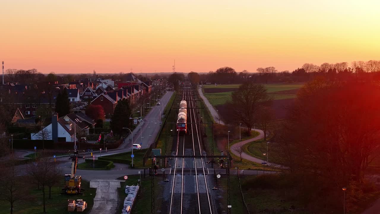 Slow Cinematic Drone Shot Looking into Sunset as Train Passes by Road Intersection