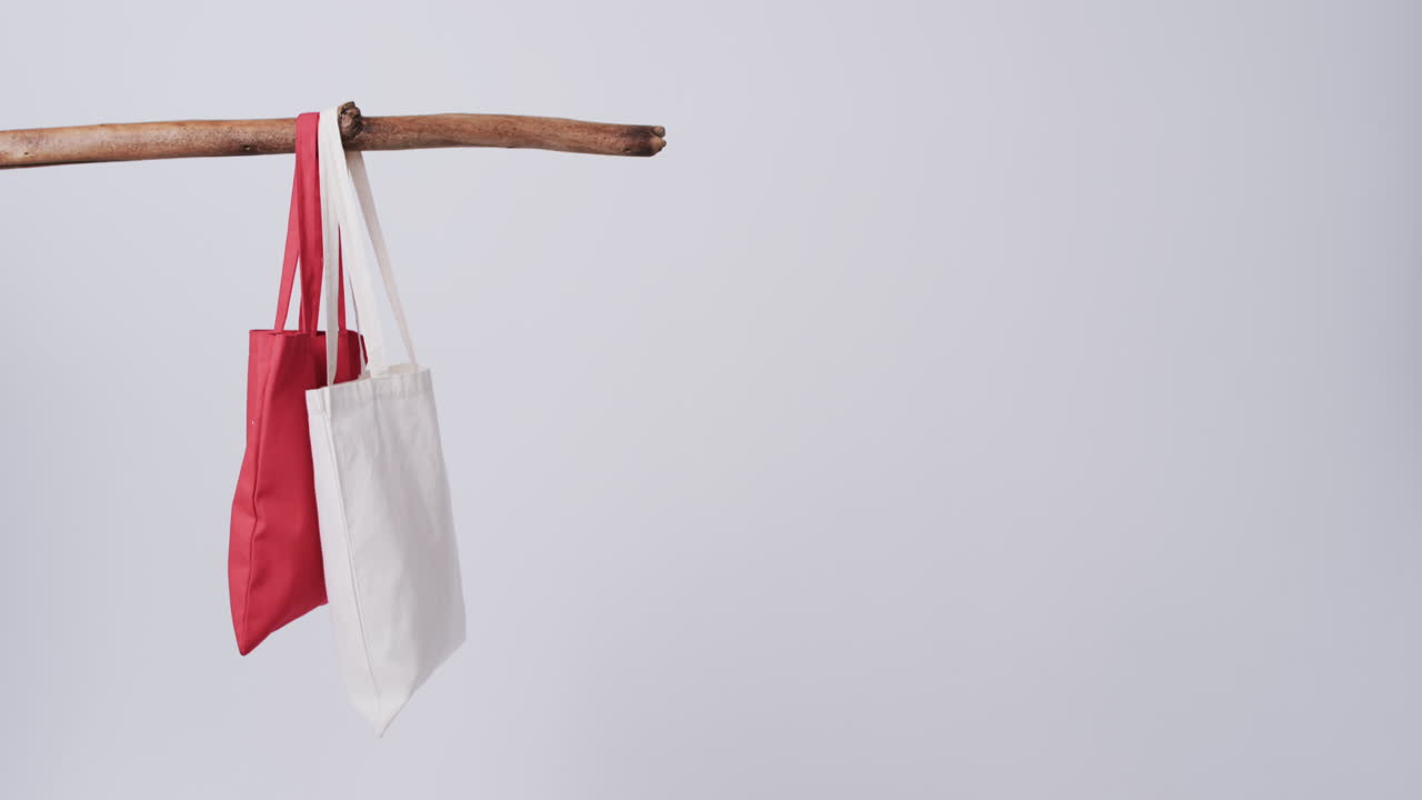 video de bolsas de lona rojas y blancas colgando de la rama con espacio de copia en un fondo blanco