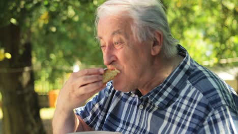 senior man eating sweet food in garden