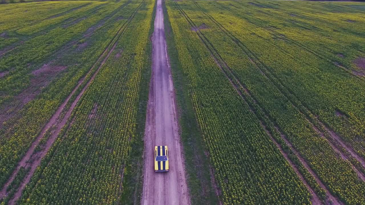 Yellow With Black Stripes Classic Ford Consul Rides On A Gravel Road. 4K Aerial Footage