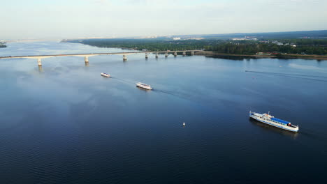 aerial view of boats on a wide river with a bridge and cityscape