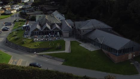 Aerial-view-circling-exclusive-old-fashioned-tavern-style-beachfront-resort-restaurant-rooftop-on-shaded-secluded-mountainside