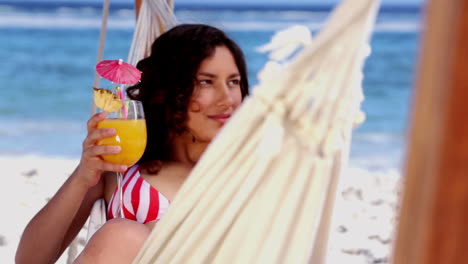 pretty girl in a hammock raising her cocktail glass