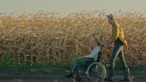 Man Pushing Woman in Wheelchair Through Cornfield