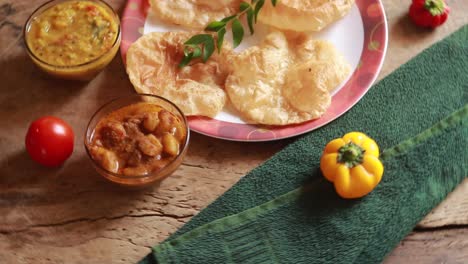 rotation chole bhature or chick pea curry and fried puri served in terracotta crockery over wood background