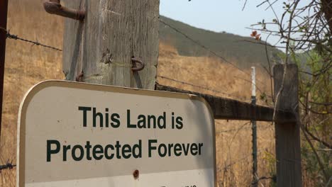 Un-Letrero-Dice-Que-Esta-Tierra-Está-Protegida-Para-Siempre,-Lo-Que-Sugiere-Conservación-Y-Ambientalismo