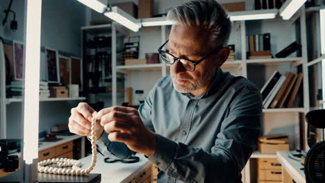 man repairing a pearl necklace