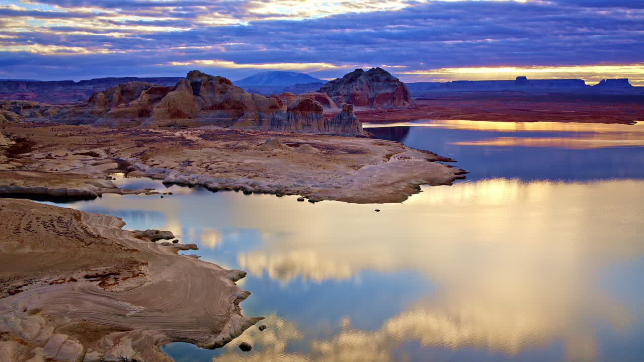 A breathtaking aerial sweep over the vast and surreal desert environment near Lake Powell, framed by towering red rock formations.