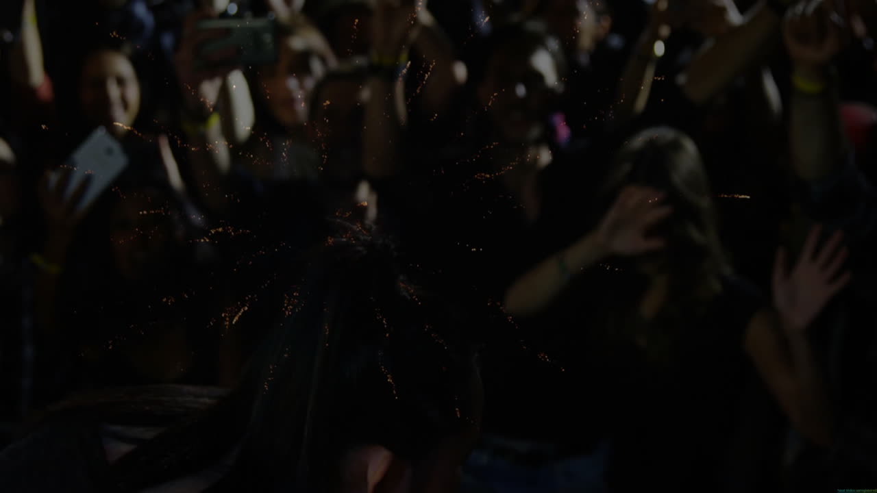 performer silhouette swinging microphone on stage, fans capturing sparks on phones for music