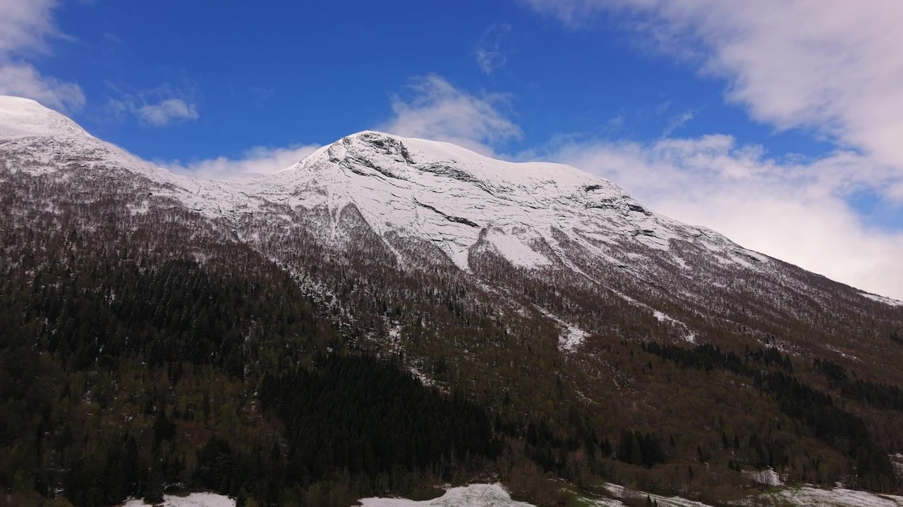Una montagna innevata si erge maestosamente contro un cielo azzurro e limpido in Norvegia. Ideale per documentari naturalistici o contenuti di viaggio incentrati sui paesaggi nordici.