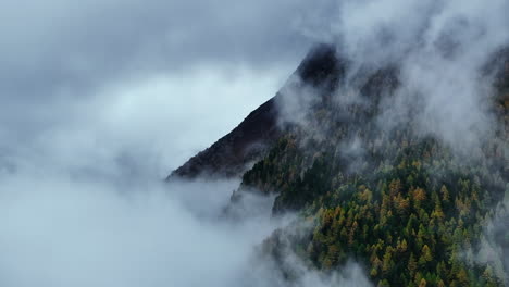 Foggy-mountainside-Saastal-Saas-Fee-Switzerland-aerial-drone-fog-layer-gray-grey-rainy-foggy-mist-fall-autumn-Swiss-Alps-peaks-glacier-valley-cloud-movement-static-shot