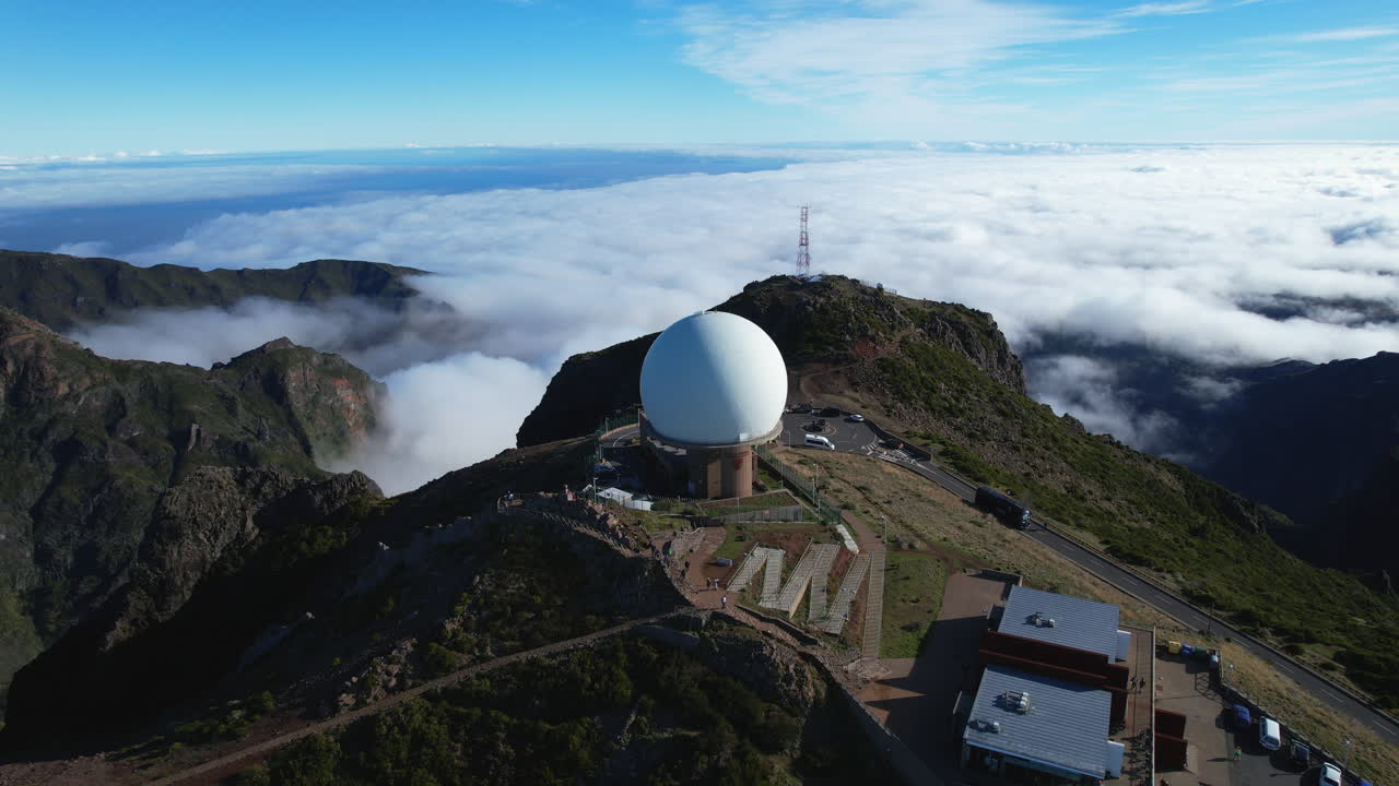 Aerial footage of the Pico do Arieiro summit with its radar dome and observatory above the clouds. Madeira, Portugal