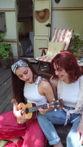 two women playing ukulele outdoors