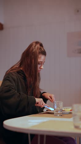 una chica comiendo en una mesa.