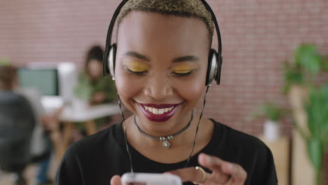 portrait of trendy young african american woman texting browsing using smartphone social media app listening to music wearing headphones