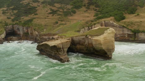 aerial orbiting shot of a sea arch coastal formation in new zealand