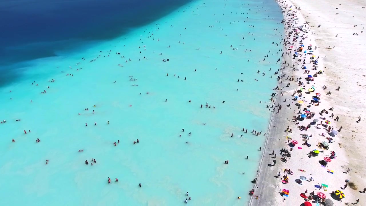 Luftfoto af overfyldt tropisk strand med turkisblåt vand
