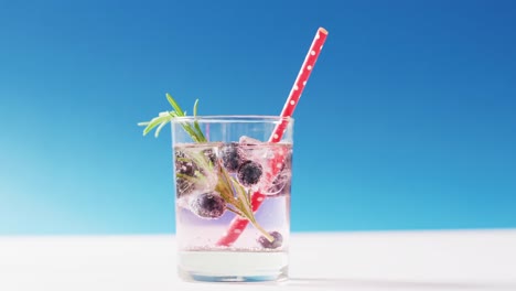 close up of transparent drink with bluberries on blue background