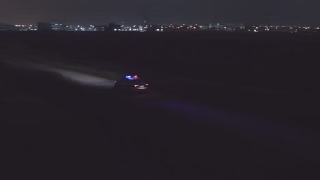 night aerial footage of a police car driving down a dark urban area