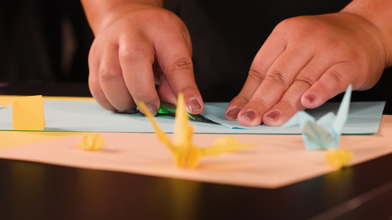 Primo piano di mani che piegano e sgualciscono con cura carta azzurra per un progetto di origami