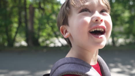 slow motion video of a young little boy in a red t-shirt walking with backpack