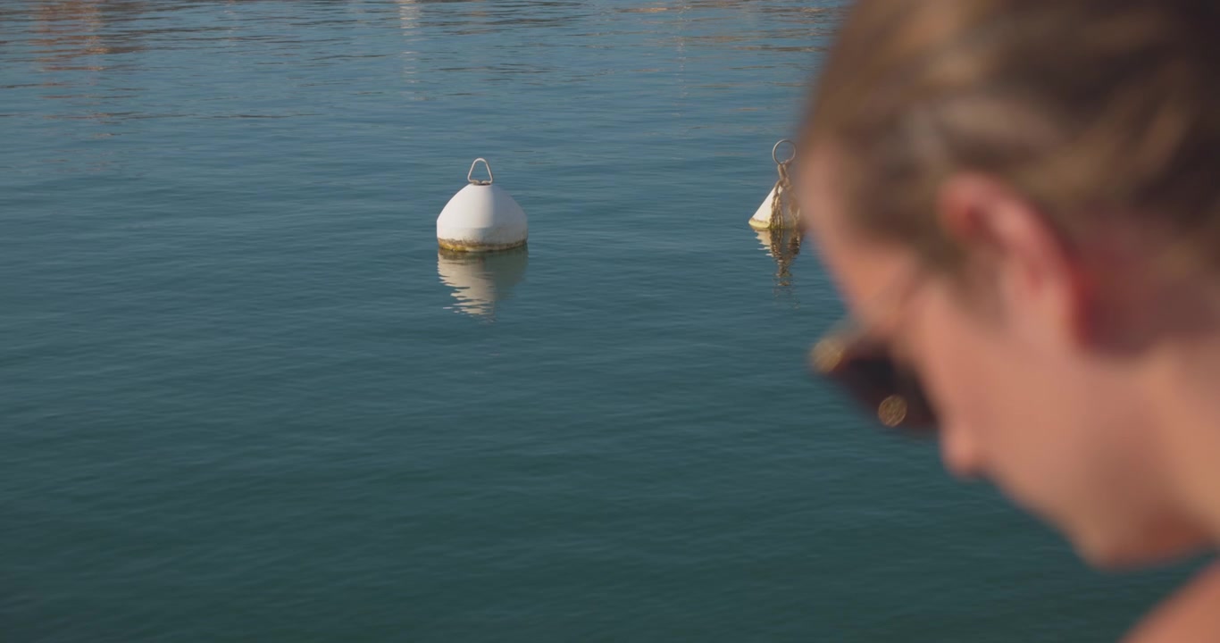A person looking into the water with white buoys in the foreground.