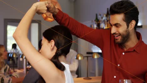 pareja sosteniendo un vaso de bebida mientras bailan en un restaurante