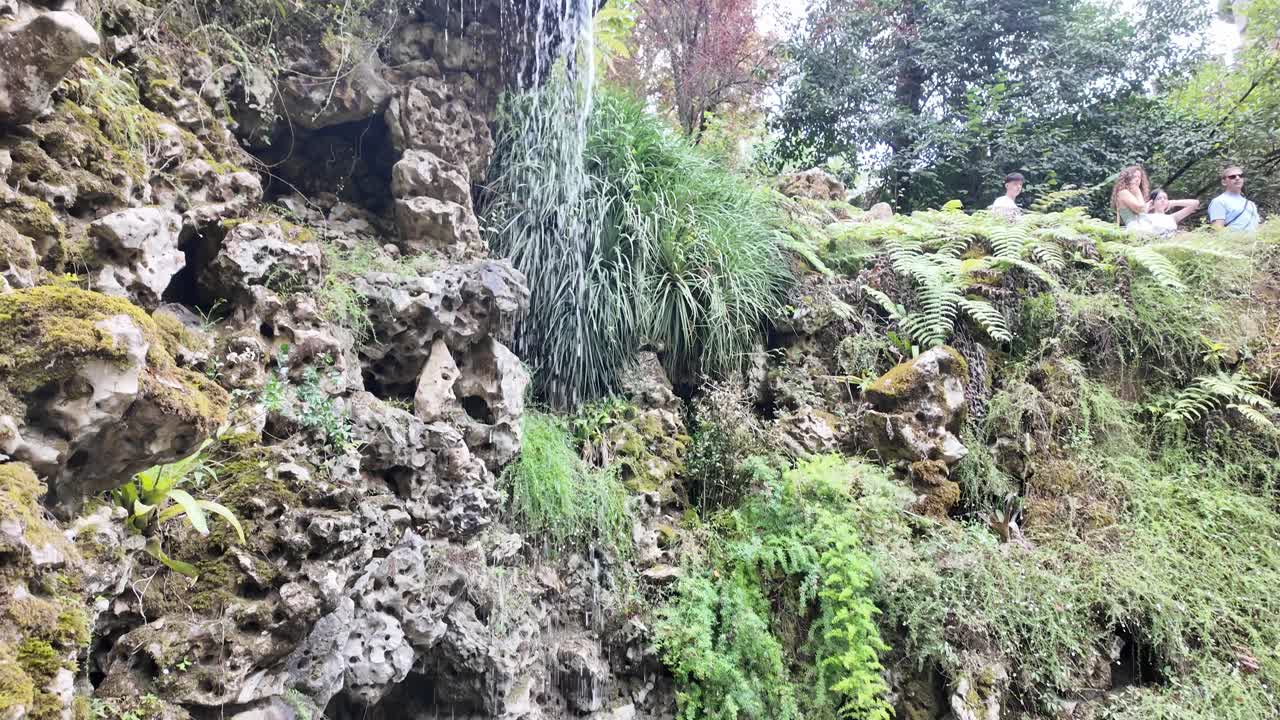 People explore lush, green gardens with rocky paths in Sintra's Quinta da Regaleira, Portugal
