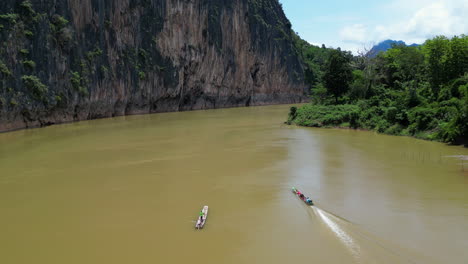 el barco de cola larga se mueve rápidamente por el barro del río mekong en luang prabang, laos.