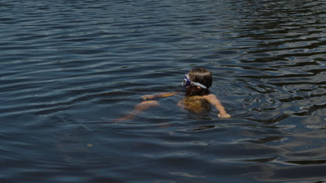 kid with goggles on head bathing in a lake