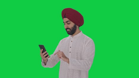 happy sikh indian man using phone green screen