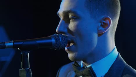 man singing song in microphone during performance on stage on rock concert. close up man rock star singer on music concert on colorful light background