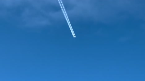 la estela de un pesado avión a reacción de 4 motores disparado desde otro avión volando bajo algunas nubes desgastadas