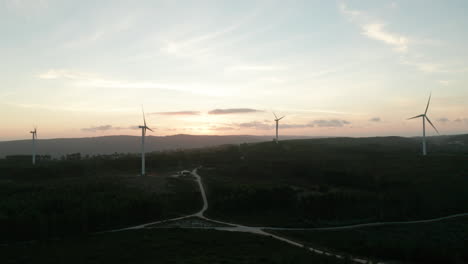 Volar-Hacia-Una-Vista-Panorámica-Con-Turbinas-Eólicas-Contra-El-Cielo-Brillante-Durante-La-Puesta-De-Sol-En-Serra-De-Aire-E-Candeeiros,-Leiria-Portugal