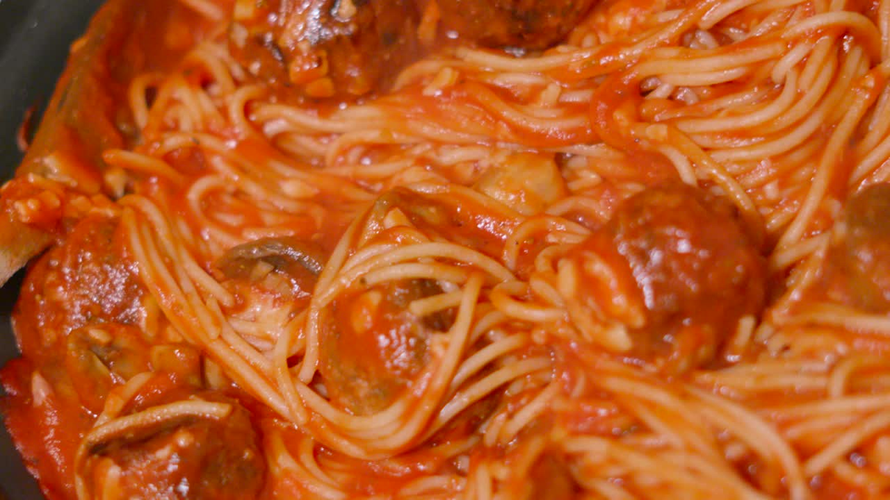 Looking Down at Italian Meatballs in Pan with Spaghetti Pasta in Rich Tomato Passata Sauce with Herbs and Mushrooms. Homemade Cooking Food Footage.