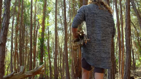 Rear-view-of-man-with-wooden-sticks-walking-in-the-forest-4k