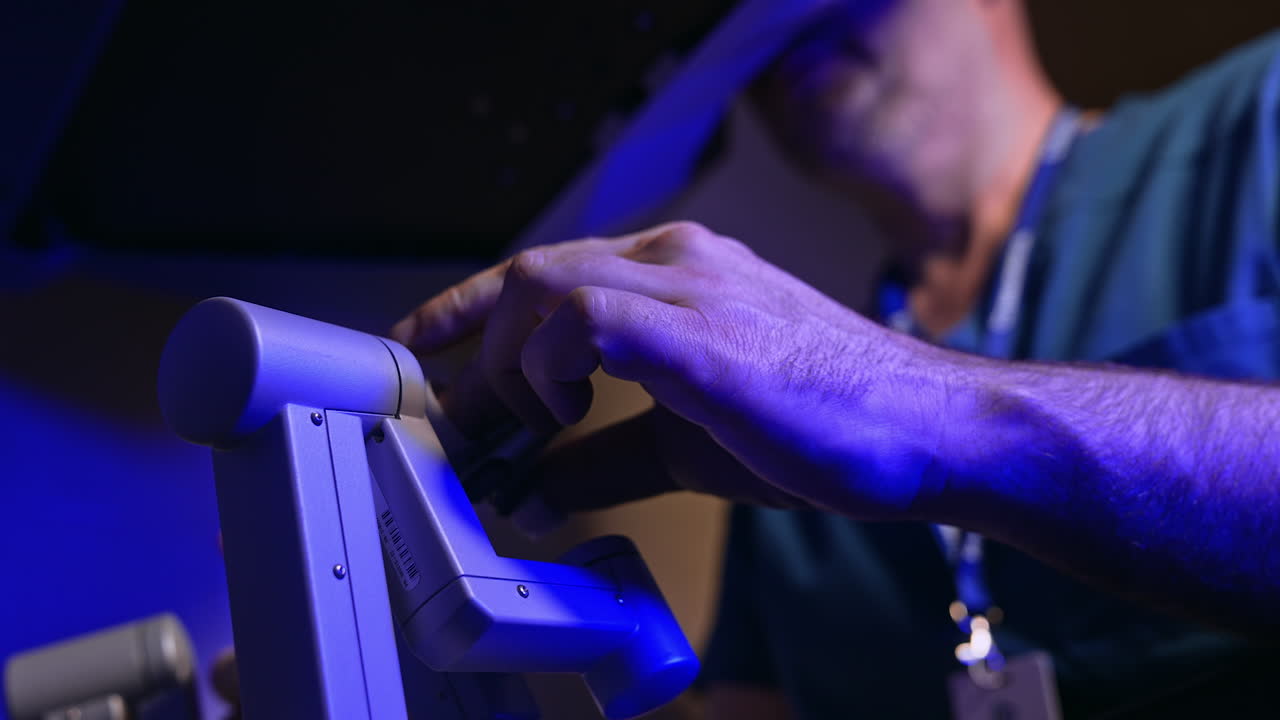 Surgery specialist operating innovative robotic equipment. Doctor looks into special binoculars and moves the handles. Close up. Low angle view.