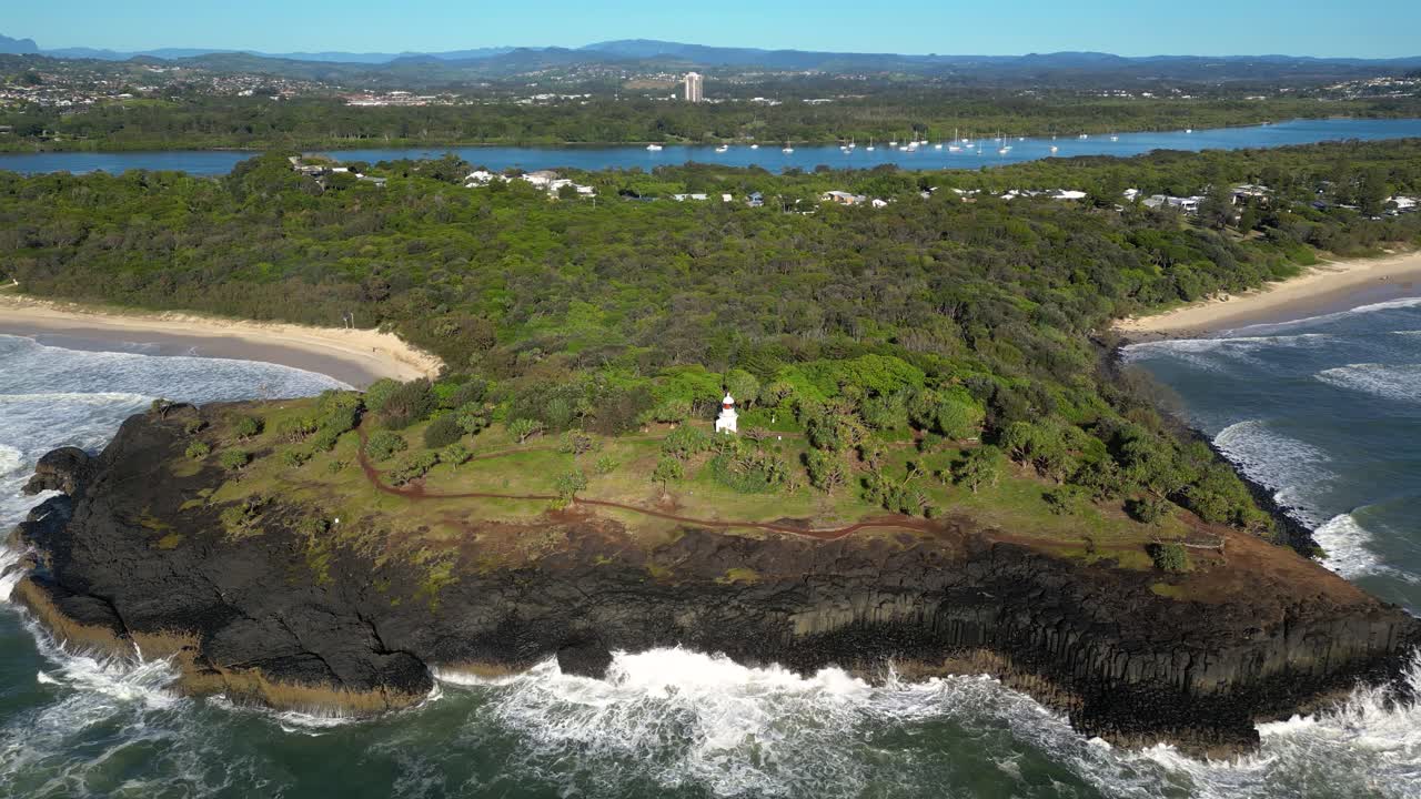 Right to left aerial looking at Fingal Head Lighthouse from over the ocean on a sunny day, Northern New South Wales, Australia.