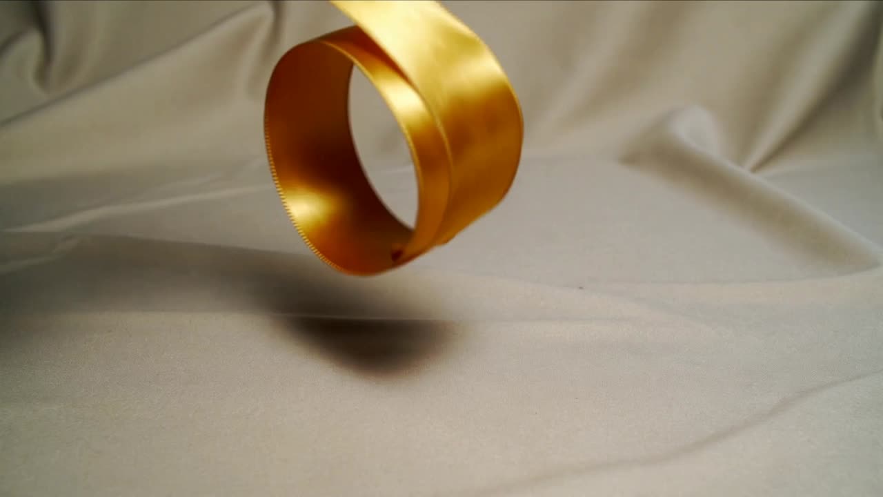 Svolgimento dopo l'estrazione da sinistra, nastro di raso dorato che forma un doppio anello su un panno beige per l'arredamento