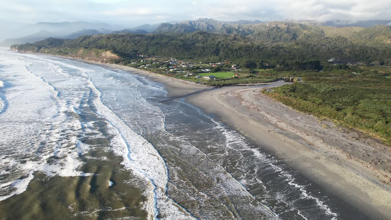 Waves Splashing On Sandy Beach Of Rapahoe With Davy Creek Mouth. West Coast Of South Island, New Zealand. aerial pullback shot