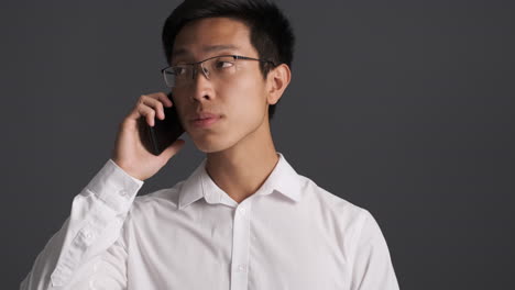 upset asian man calling on smartphone.