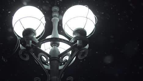 farola brillante en la noche nevada. cerrar la linterna de la calle en los copos de nieve nocturnos