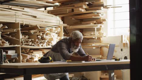 african american male carpenter sketching a project in a carpentry shop