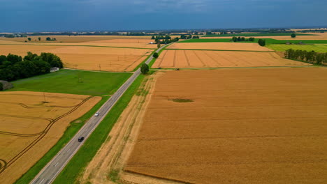 Pan shot of a highway passing through agriculture fields on a cloudy day. Aerial view.