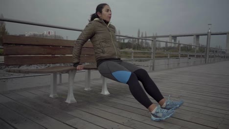 Serious-hindu-sportswoman-doing-exercises-near-wooden-bench